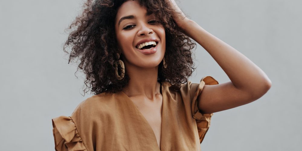 Portrait,Of,Curly,Brunette,African,Dark-skinned,Woman,In,Beige,Top smile design alexandria